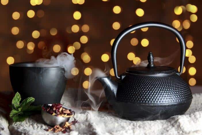 Hot steaming tea in a cup and kettle