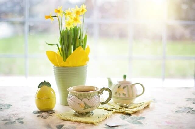 A table set with a tea cup, tea pot and daffodils