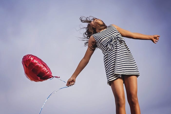 A happy girl letting go of balloon.